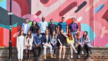 a large group of students are infront of a bright mural 