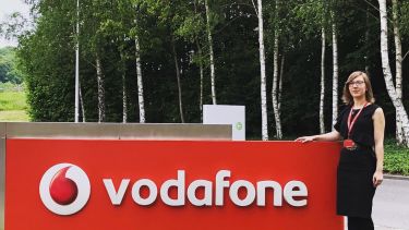 Laura Craciun, computer science alumni standing by a Vodafone sign
