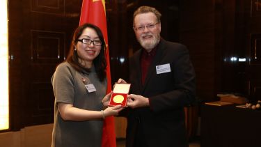 Lisa Wang receiving her Distinguished Alumni Award from Professor Sir Keith Burnett