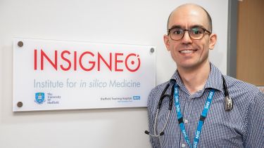 A researcher stood in front of an INSIGNEO sign