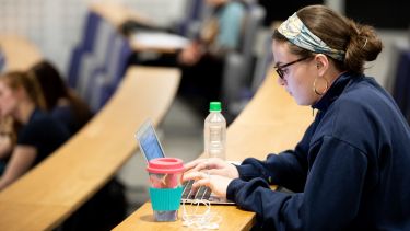 An undergraduate medical student making notes in a lecture