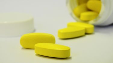 A photograph of yellow tablets on a white surface.