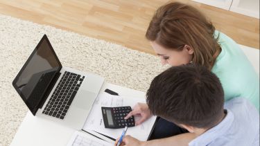 Photo of man and woman working on a calculator at home