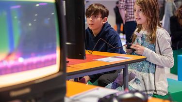 Two children playing games at the National Video Game museum.