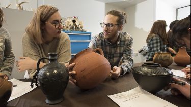 Two archaeology students examine ancient pots in a seminar.