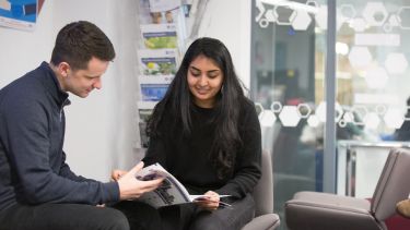 Two students reading a brochure in the employability hub