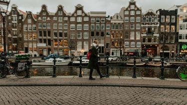 Woman walking alongside canal in Amsterdam
