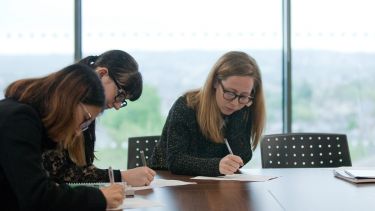 Students sat at a table writing.