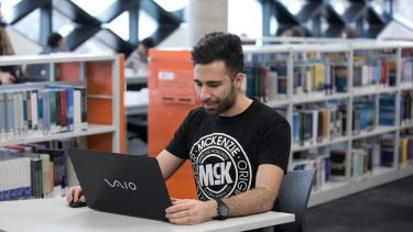 An engineering student using a laptop in the Diamond.