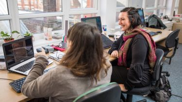 Two PhD students researching on laptop 