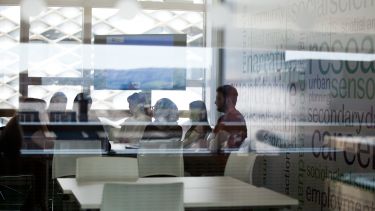 Students in a discussion viewed through glass