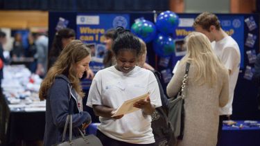 Two students reading a brochure at the Global Opportunities Fair.