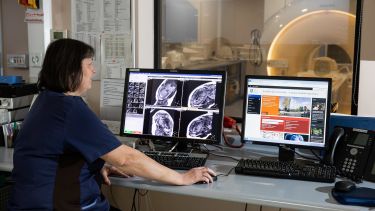 A woman checks the results of an MRI scanner.