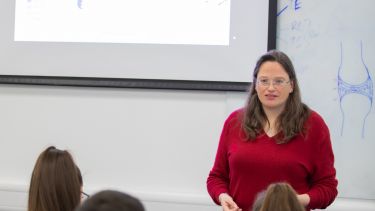 A lecturer in Oncology speak to students from the front of the class. 