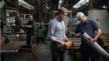 Two men looking at a pipe in a factory