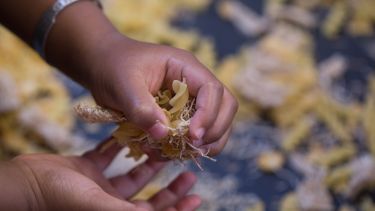 Photograph of child playing with pasta and straw