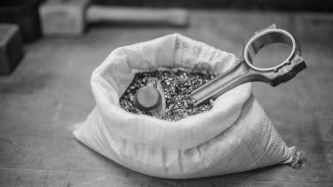 A grayscale image of a bag of swarf with two formed components sticking out