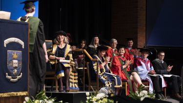 PG student shaking hands with chancellor on stage