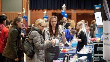 Three women at a supplier exhibition stall, displaying laboratory goods.