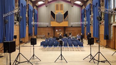 An empty hall with large speakers at the back of it.