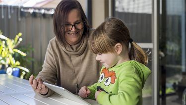 A parent and child are using an iPad together - image 