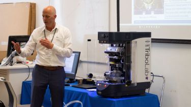 Presenter speaking in front of the TriboLab characterisation equipment