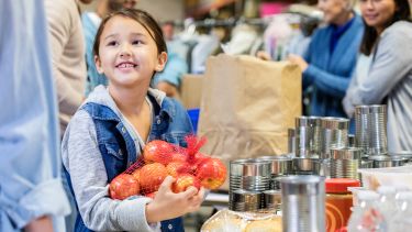Picture of a girl holding a bag of apples in a food bank