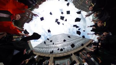 Graduates throwing their mortarboards in the air outside the Arts Tower