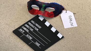 A theatrical mask with a tag that says director. There is also a black clapperboard.