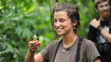 Image of a person holding a small exotic bird while on a field trip in Borneo