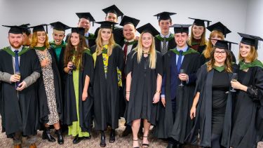 MA Journalism students in their graduation gowns pose for a group photo. 