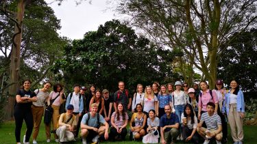 A group of students and staff pose for photo against trees in Durban park