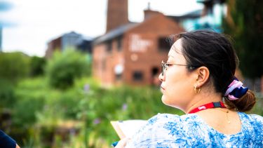 Student observing surroundings against backdrop of old industrial chimney