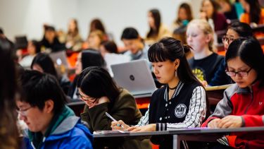 Students sat in a lecture taking notes