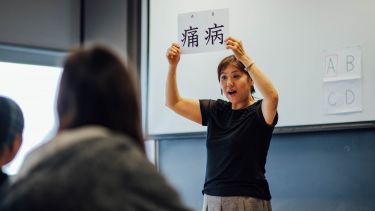 A lecturer showing students a card with two Chinese characters on