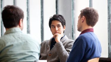 Student listens in group discussion against frosted glass wall