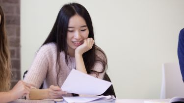 A student smiling and looking down at her notes in a seminar