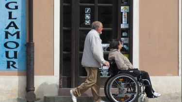 Photo of a person walking pushing someone in a wheelchair 