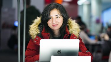 An Information School student with her laptop smiles at the camera.