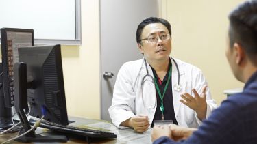 A doctor talking to a patient sat next to a computer