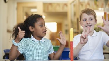Two primary school-aged children counting on their fingers