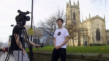 A journalism student doing a piece to camera. Another student holds the mic and works the camera.
