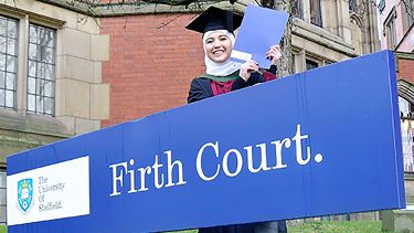 Nora stood in front of the Firth Court sign at her graduation