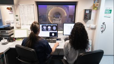 A student and doctor looking at an MRI scan on a computer screen