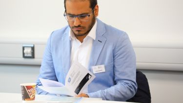 A postgraduate research student reading a brochure at the postgraduate research conference.