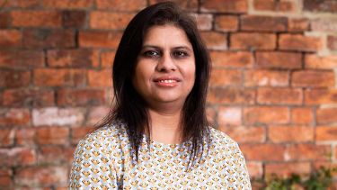 A photo of Dr Parveen Ali in front of a brick wall - image