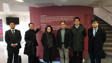 Members of AREC stood together in front of a wall sign about the centre's mission and vision