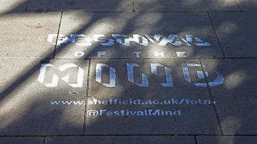 Festival of the Mind logo spray-painted in white onto paving stones