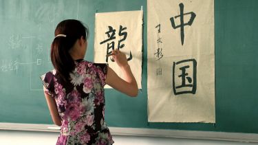 Student writing Chinese on a wall