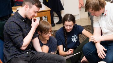 Undergraduate students gathered round a piece of paper, talking